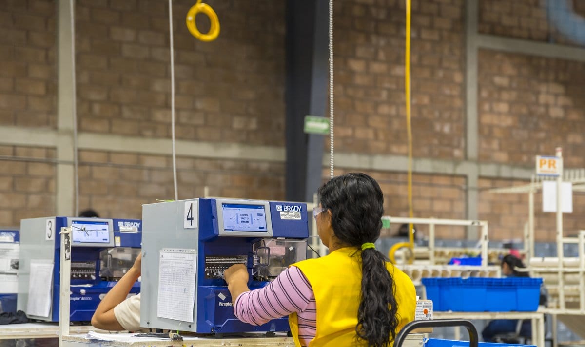 Production employee operating labeling equipment at a manufacturing plant in Mexico | Tetakawi