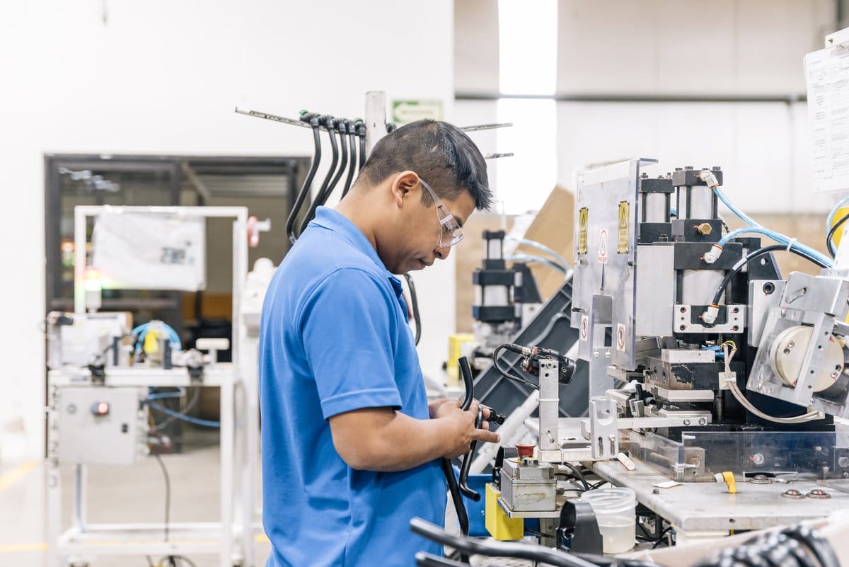 A technician connects a hose fitting on a precision assembly line at a manufacturing plant in Mexico | Tetakawi