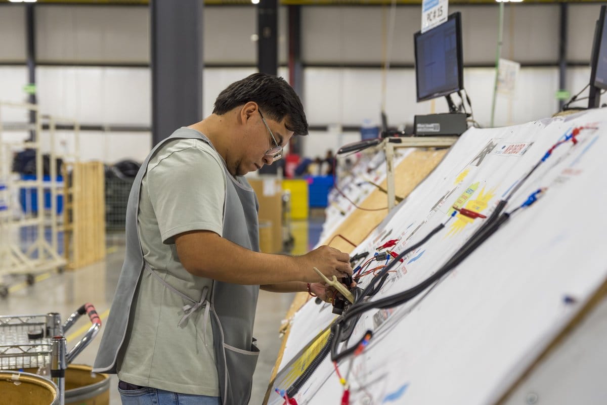 A technician assembles a wire harness on the production floor of a manufacturing plant in Mexico | Tetakawi