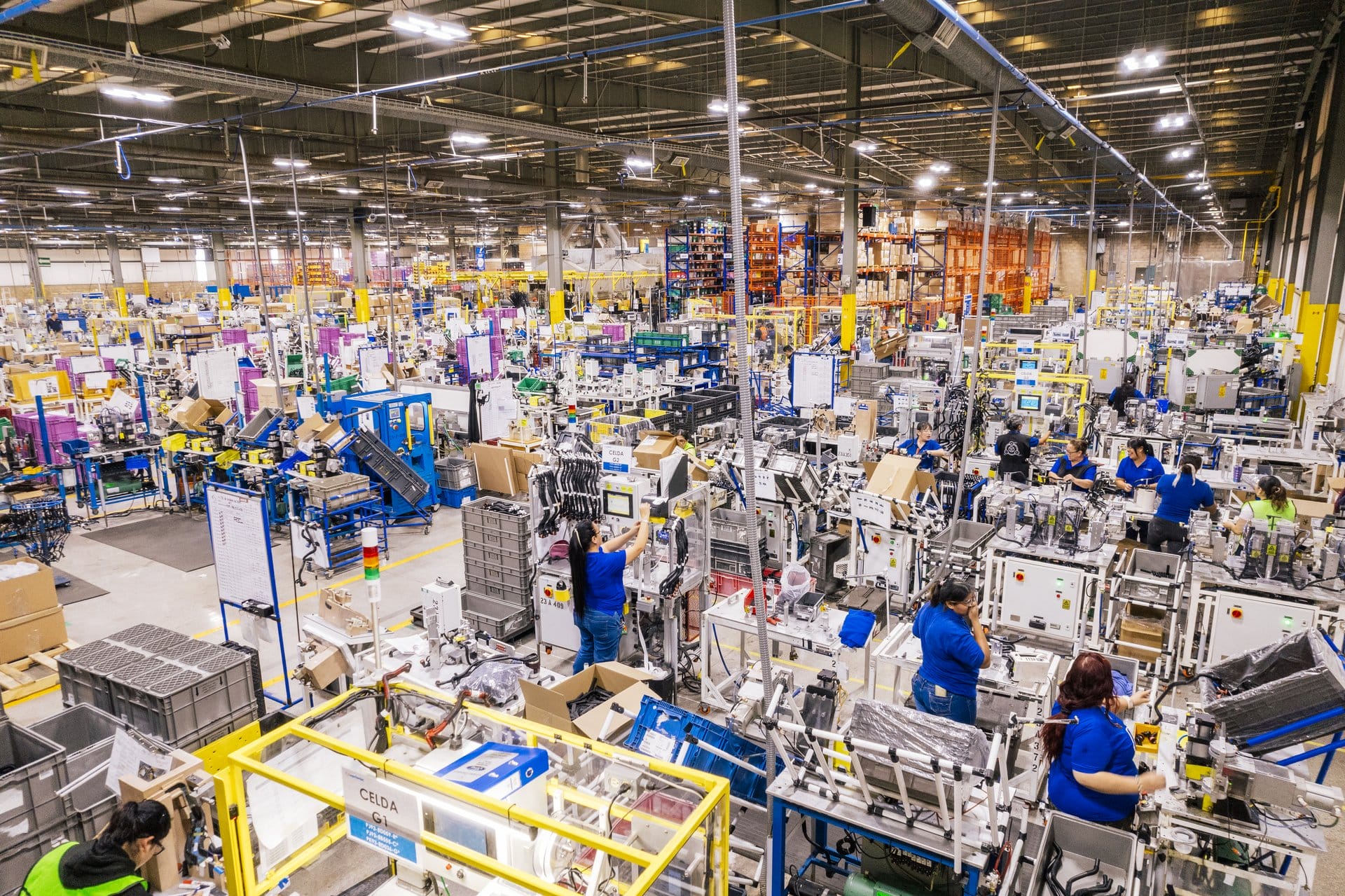 Wide view of a bustling manufacturing assembly line floor with workers and organized production cells in Saltillo, Mexico | Tetakawi
