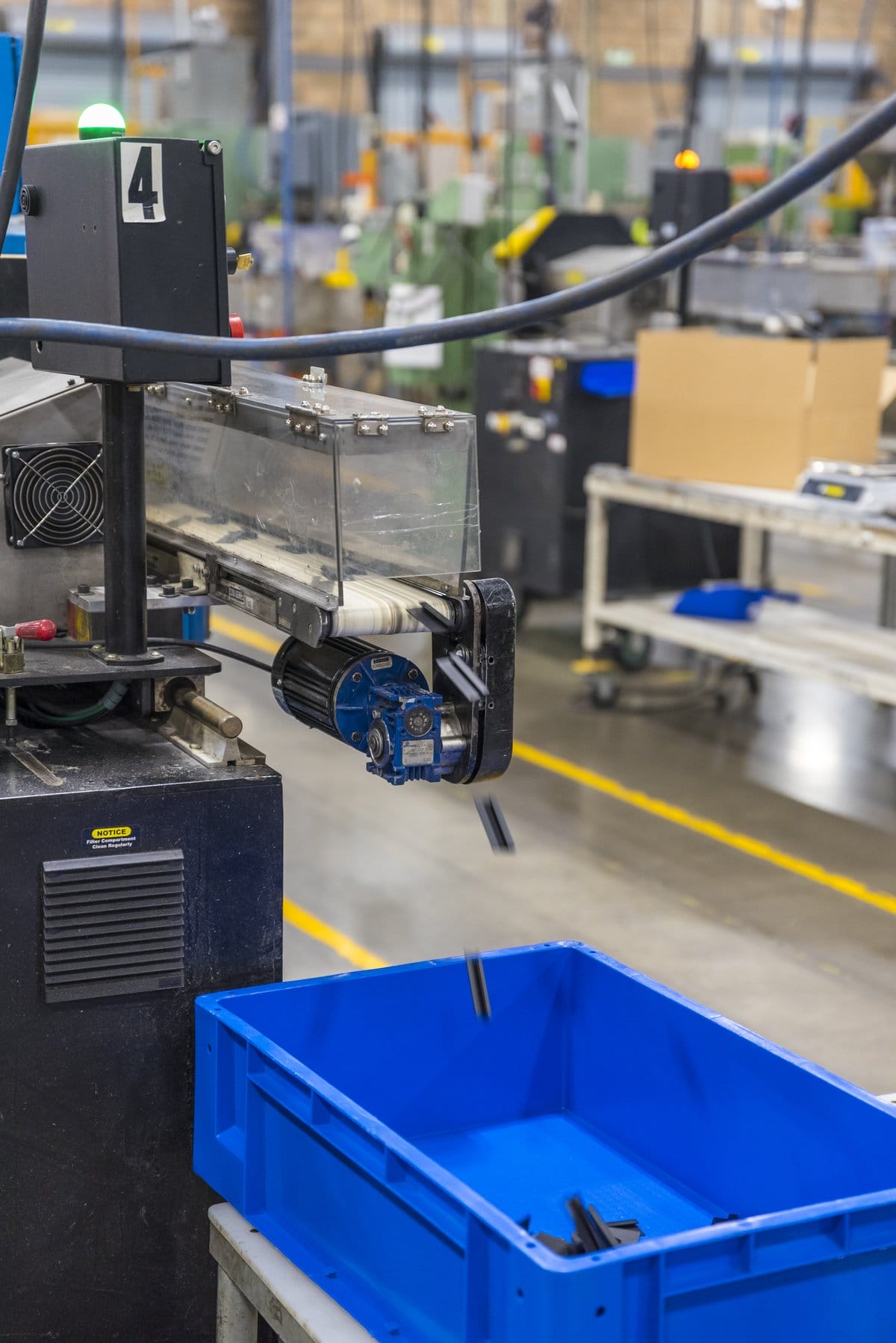 Automated machine dropping finished metal parts into a bin on a manufacturing production line in Mexico | Tetakawi