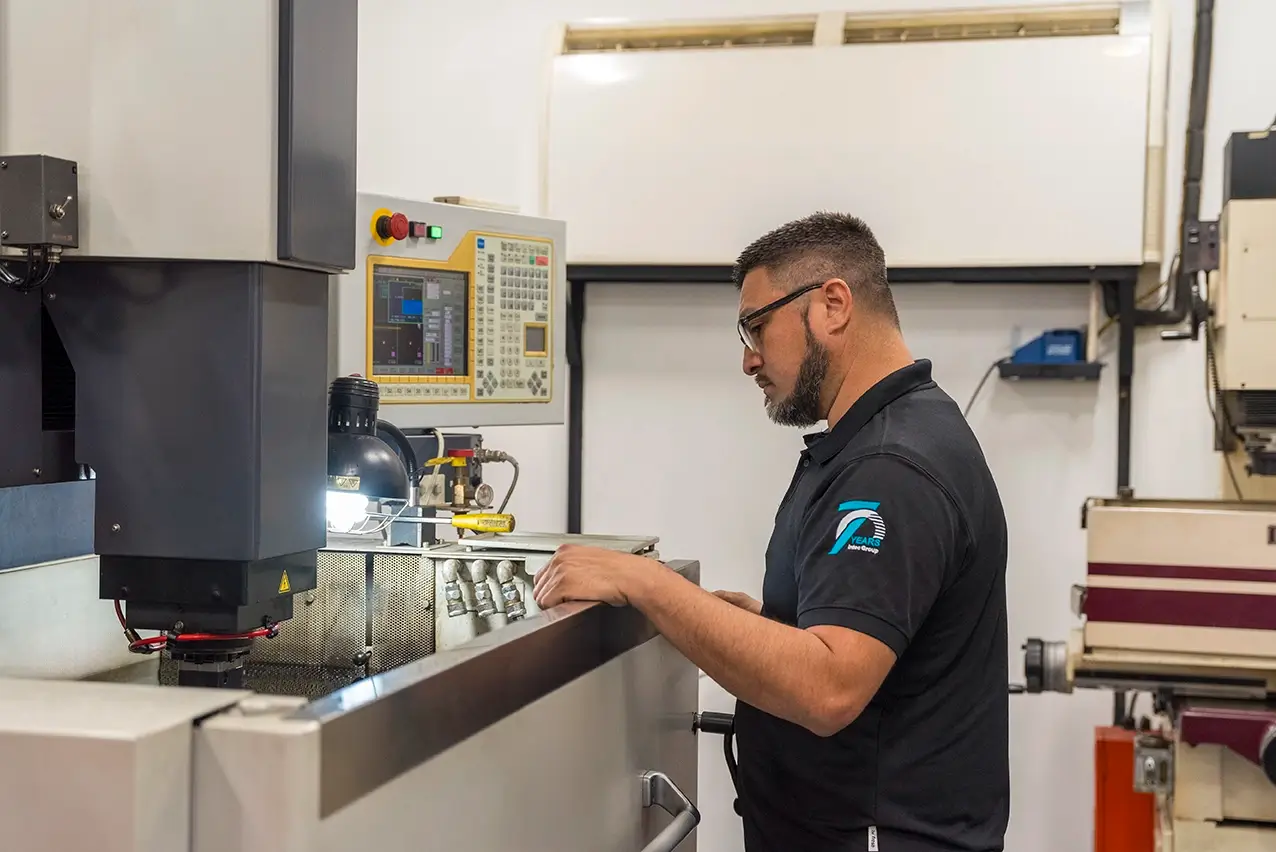 Machinist in safety glasses operating precision machining equipment on a manufacturing floor in Mexico | Tetakawi
