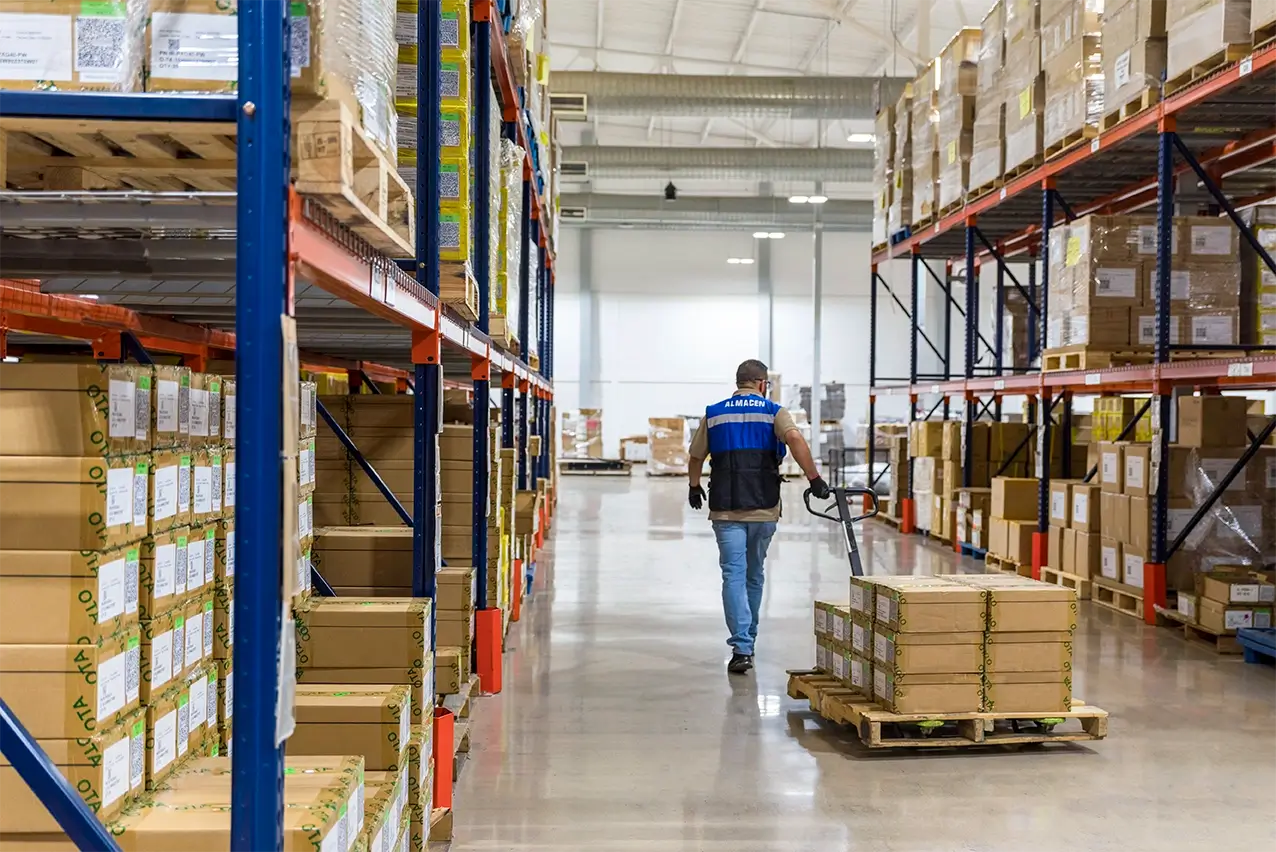 Material handler pulling a pallet of boxes through tall racking aisles at a manufacturing operation in Mexico | Tetakawi