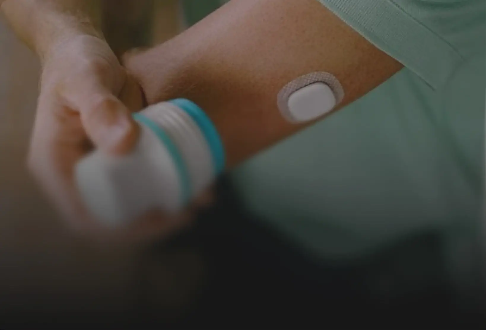 Person applying a wearable medical sensor to the upper arm, representing medical device manufacturing in Mexico | Tetakawi