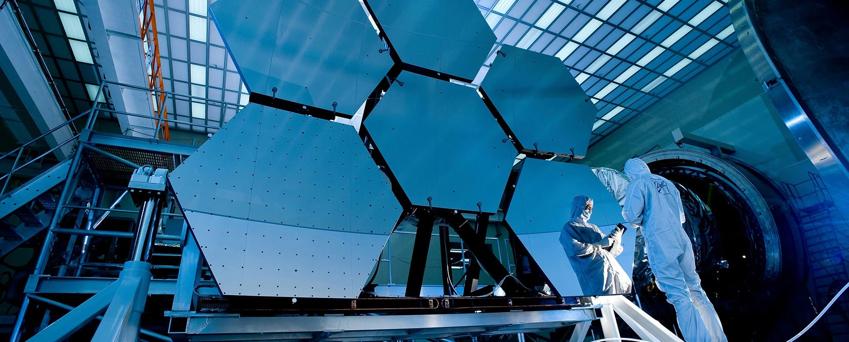 Technicians in cleanroom suits working on large precision hardware | Tetakawi