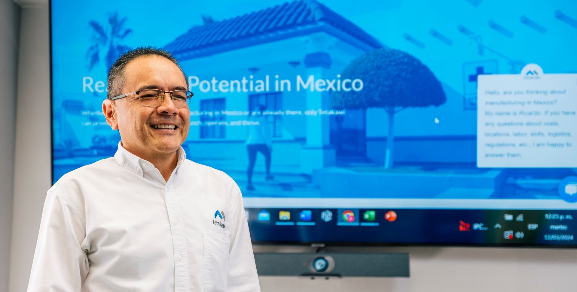 Smiling Tetakawi team member in front of a screen showing the Tetakawi website about manufacturing in Mexico | Tetakawi