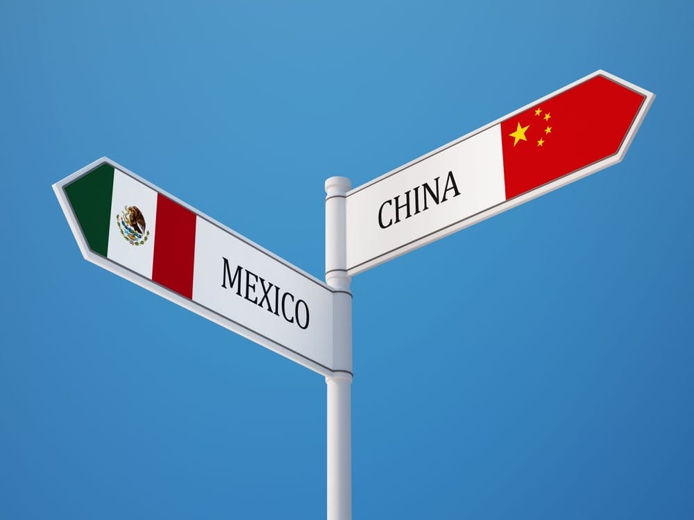 Signpost with Mexico and China flags pointing in opposite directions, representing a manufacturing crossroads | Tetakawi