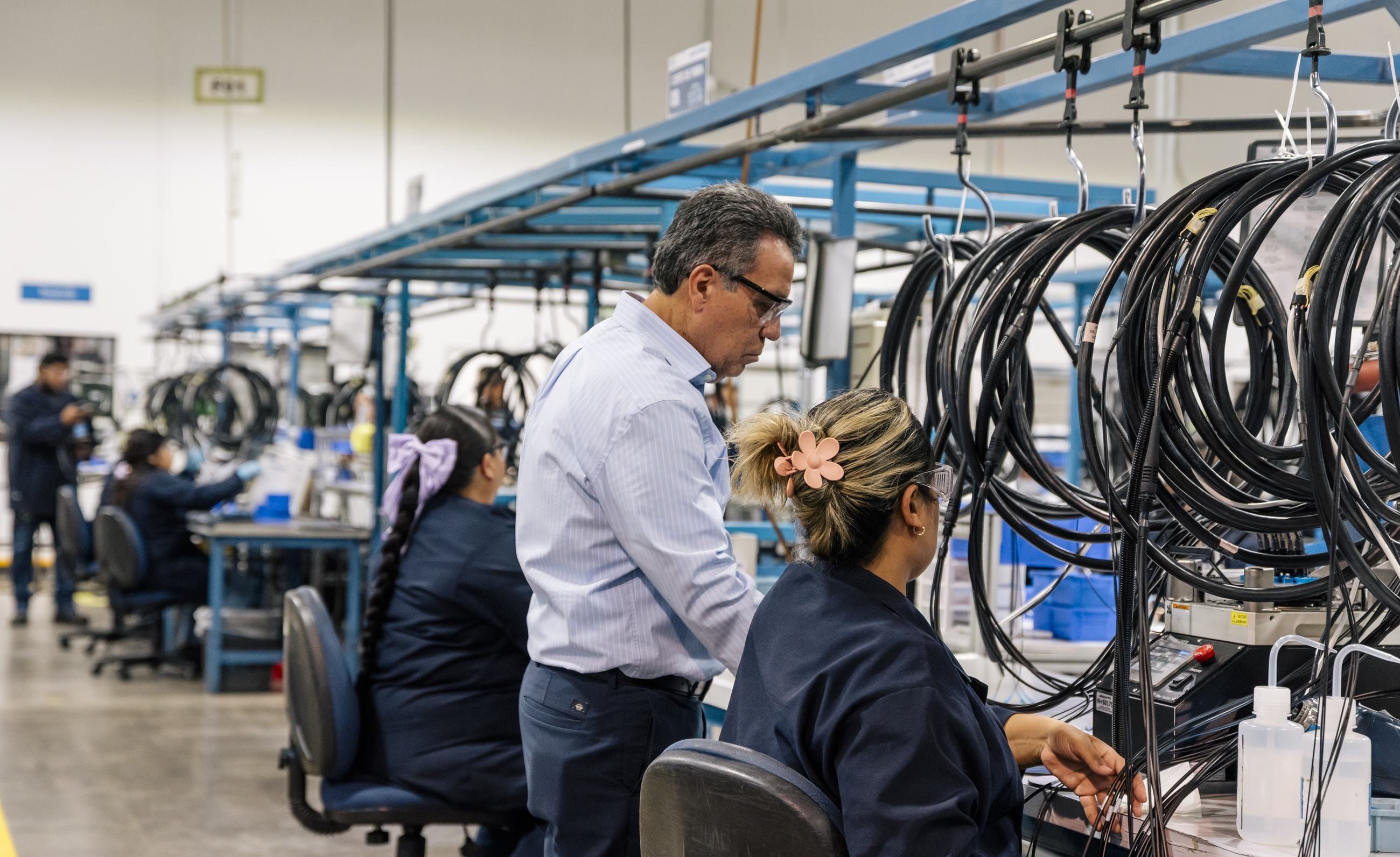 HUBER+SUHNER plant manager reviewing cable harness assembly work with team members at a Tetakawi Manufacturing Campus