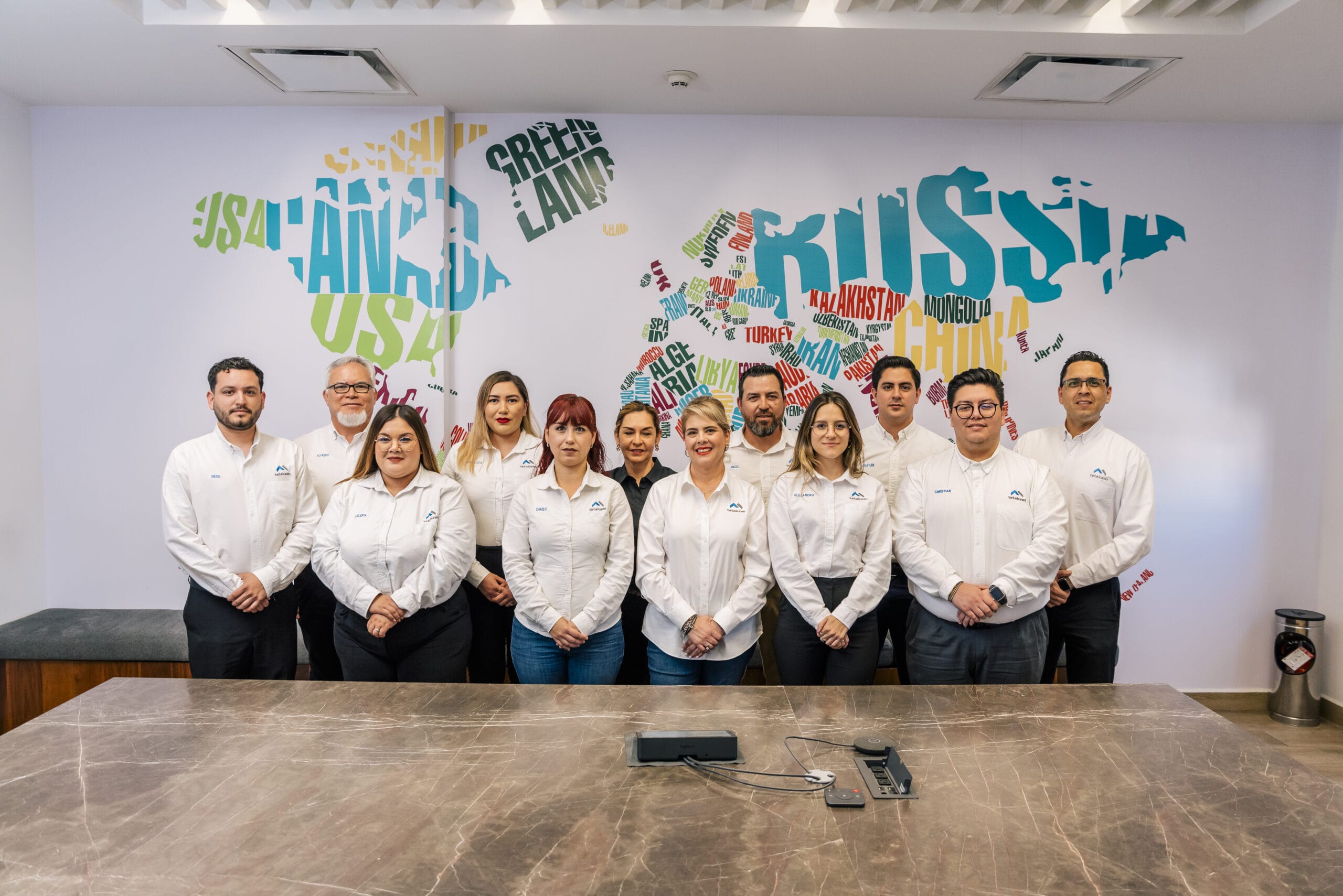 Tetakawi team members in branded white shirts gathered in a conference room, supporting manufacturing in Mexico | Tetakawi