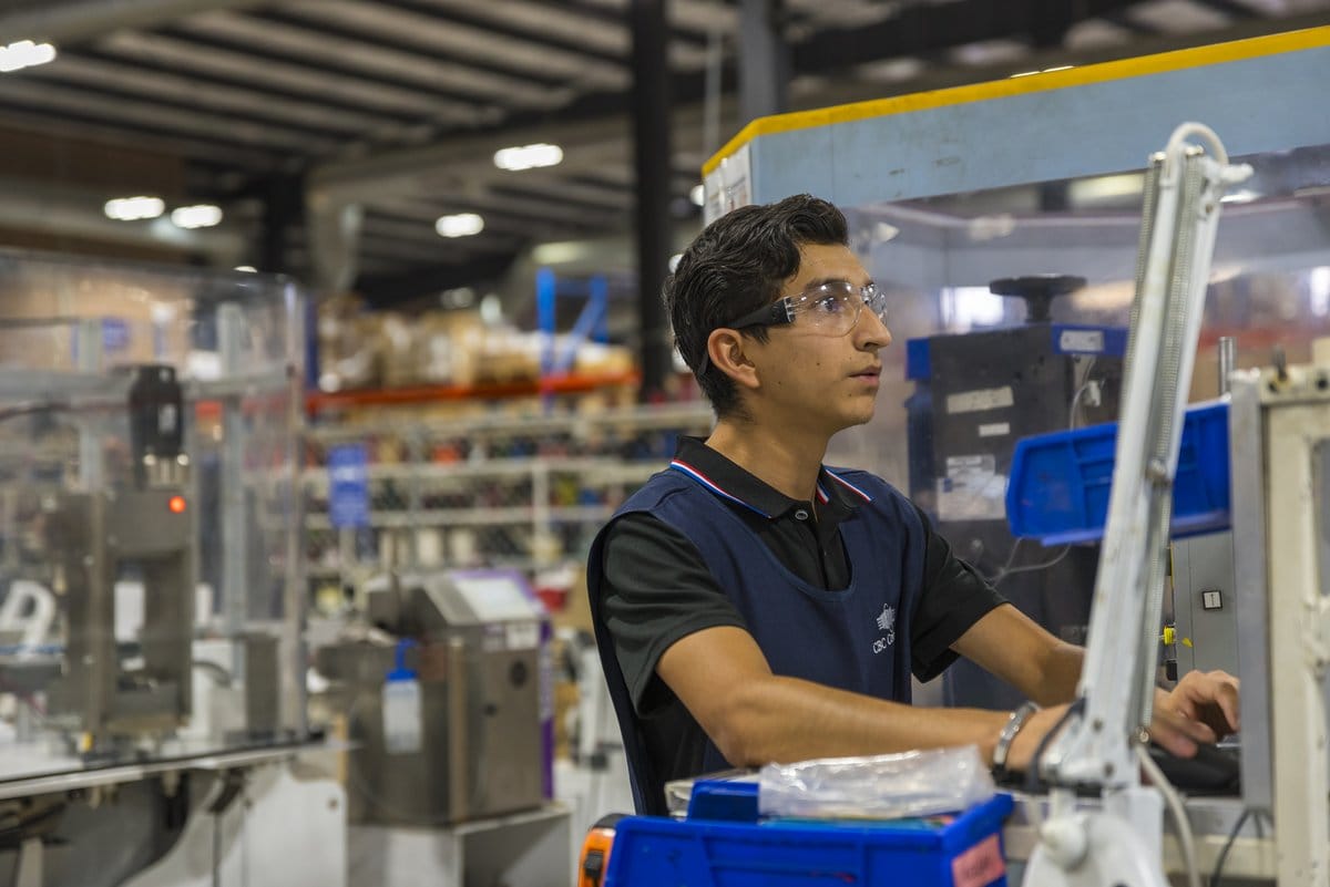 A Tetakawi technician operates production equipment on a Manufacturing Campus floor in Mexico | Tetakawi
