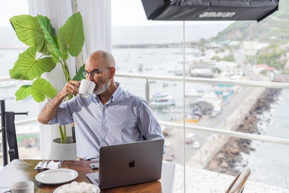 Business leader reviewing manufacturing sector data on a laptop overlooking a coastal Mexican port | Tetakawi