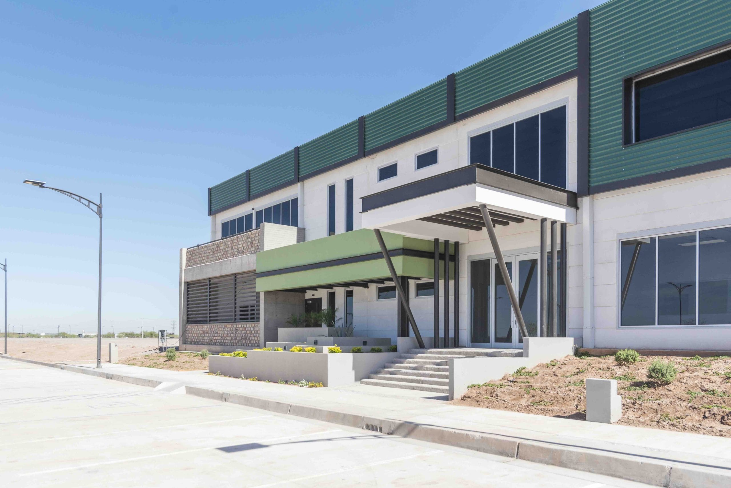 Modern industrial building with green cladding and a glass entrance, industrial space for manufacturing in Mexico | Tetakawi