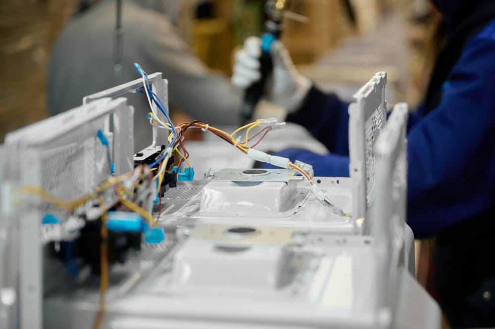 Worker assembling wire harnesses on an appliance production line at a Tetakawi Manufacturing Campus in Mexico | Tetakawi