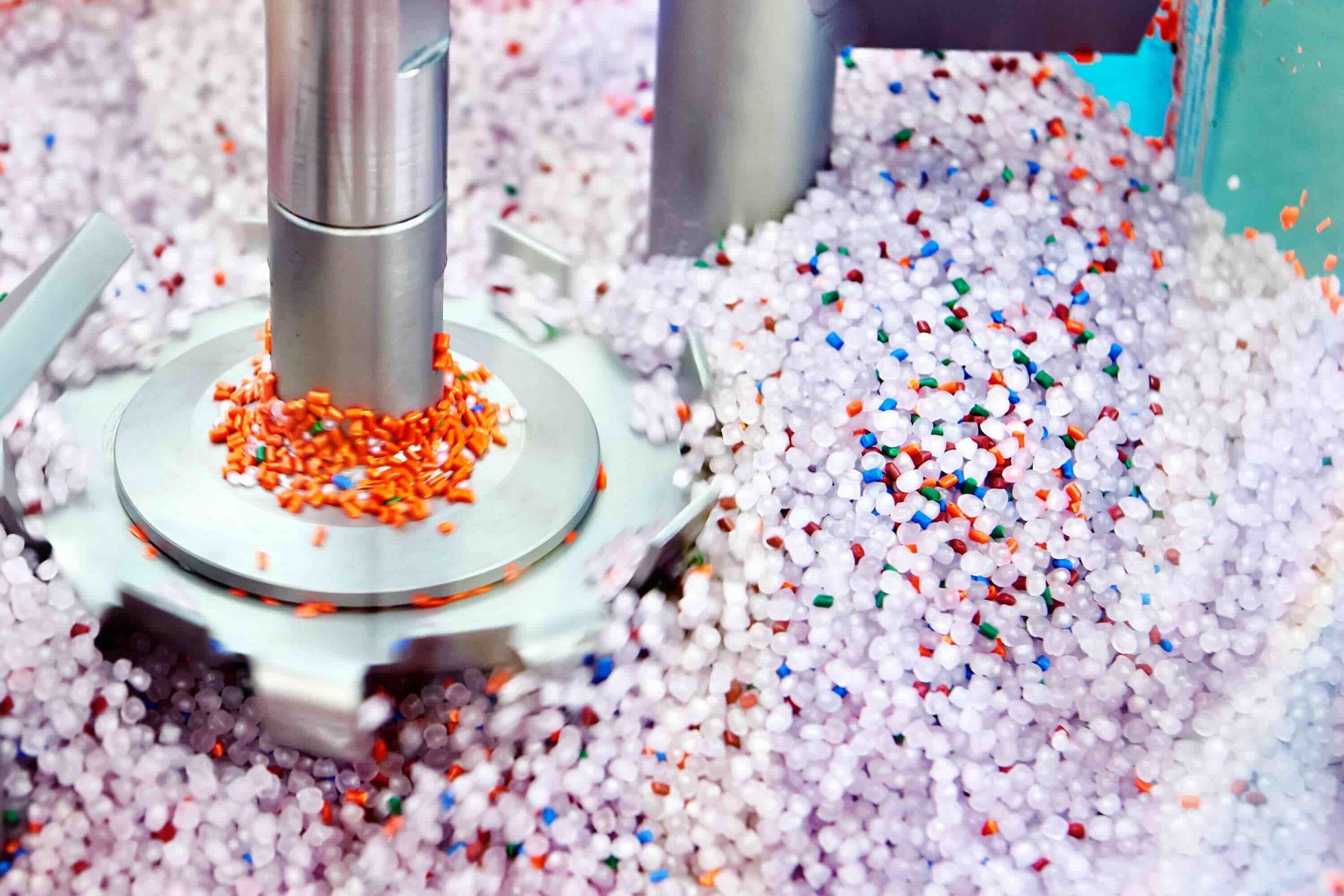 Colorful plastic resin pellets mixed by a stainless steel blade, representing plastics manufacturing in Mexico | Tetakawi