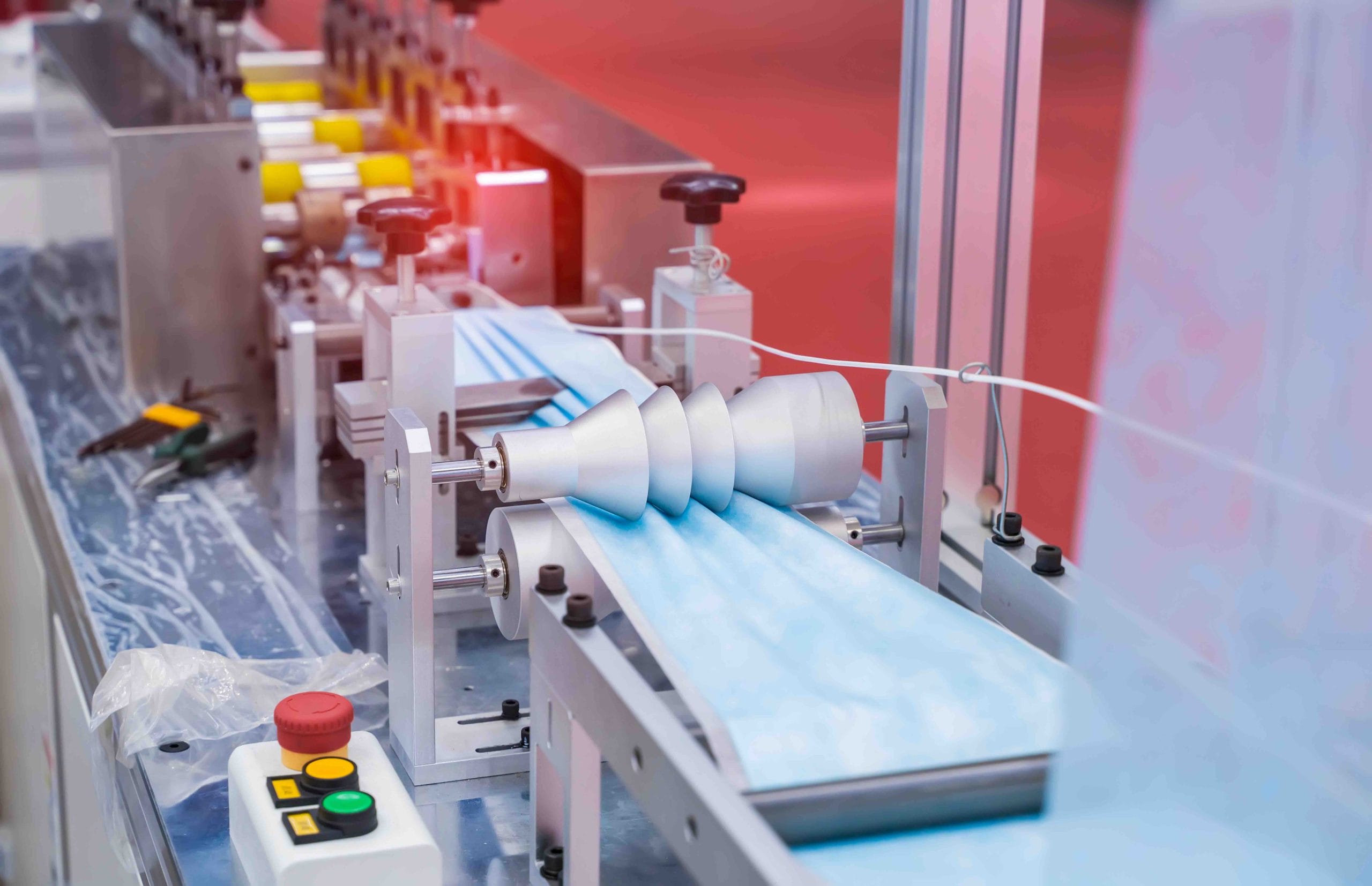 Machine folding blue nonwoven fabric for disposable face masks, showing medical device manufacturing in Mexico | Tetakawi