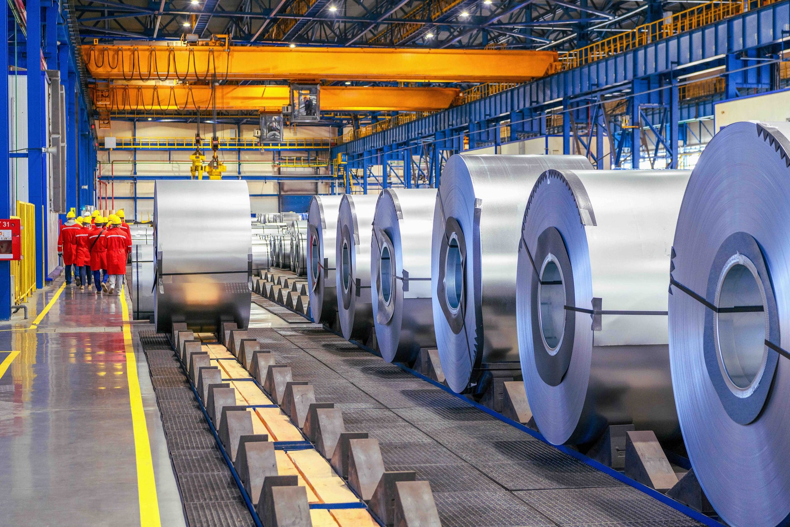 Rolled steel coils lined up in a factory hall with overhead cranes, tied to automotive manufacturing in Mexico | Tetakawi