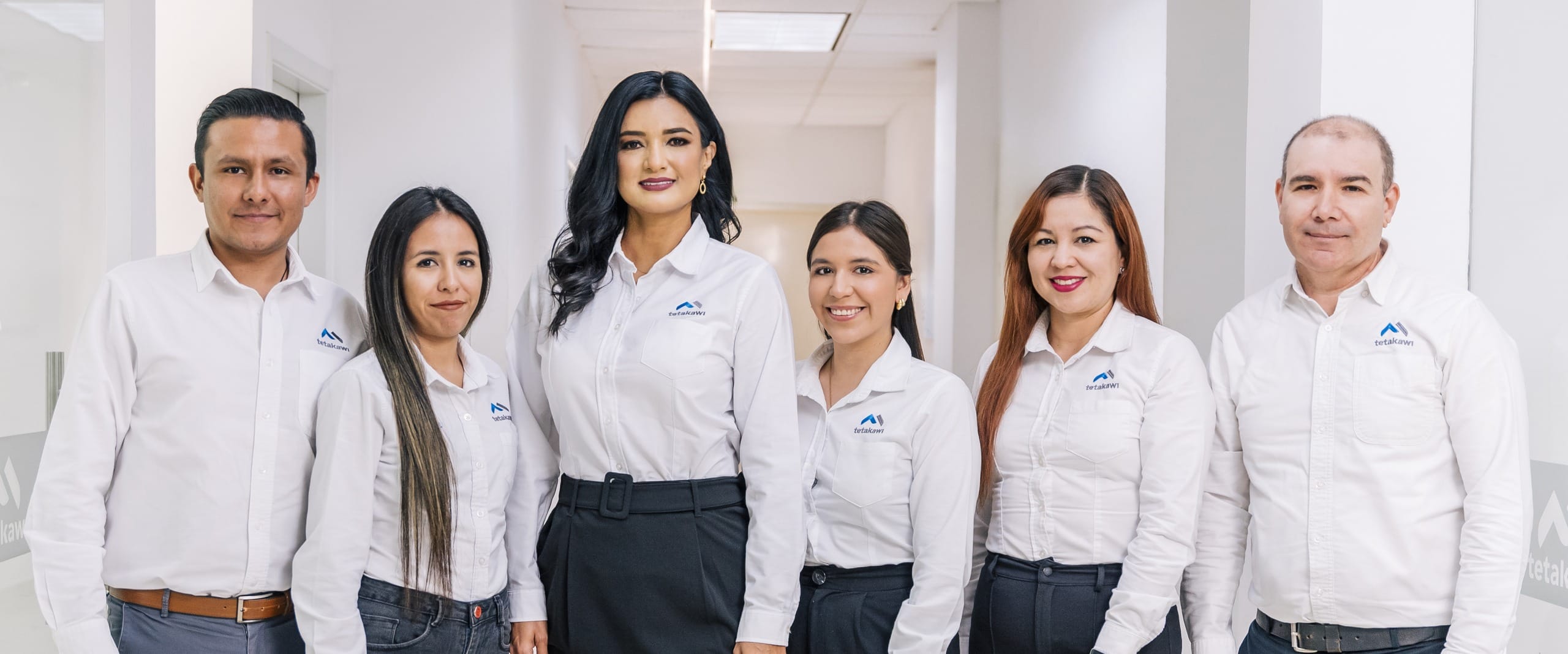 Tetakawi compliance team standing in a manufacturing campus office hallway in Mexico
