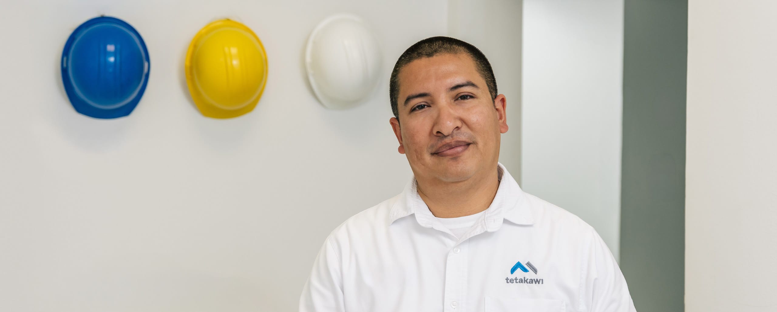 Tetakawi EHS compliance team member in front of hard hats at a manufacturing campus in Mexico