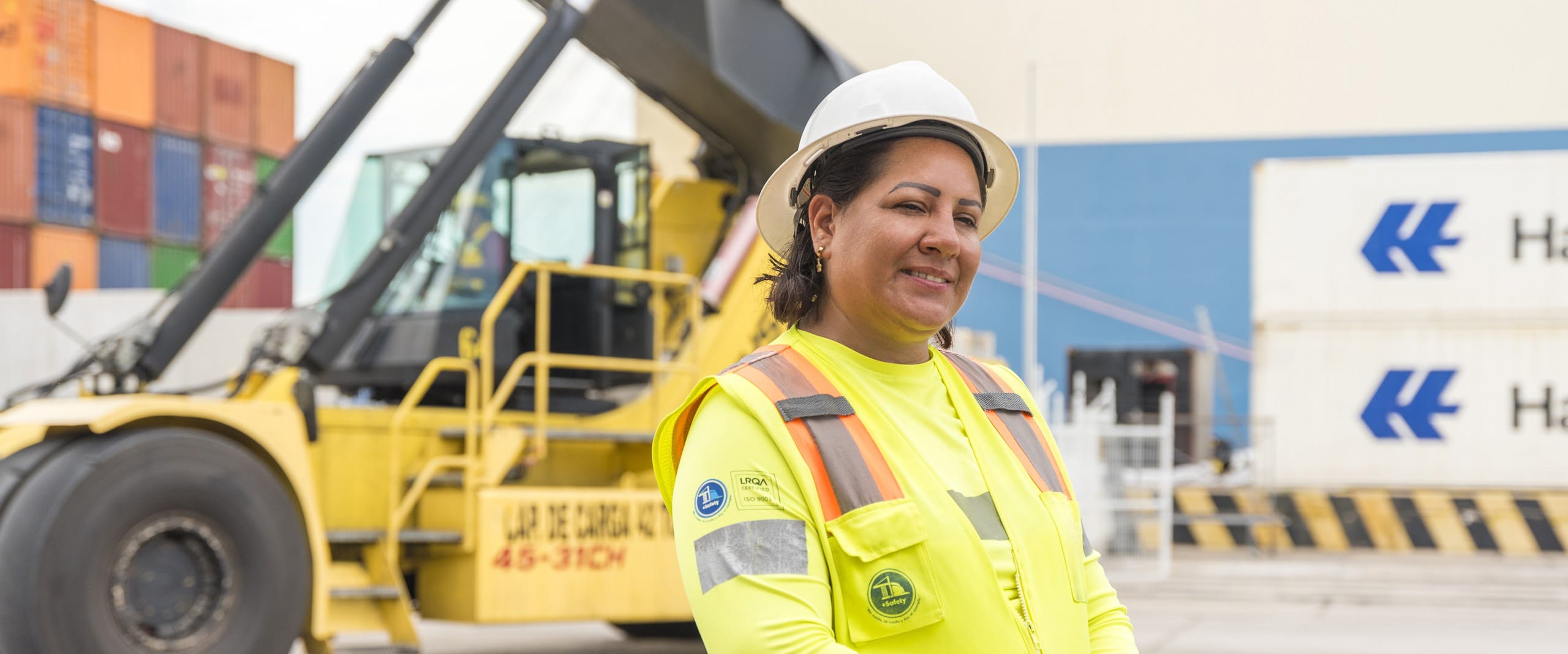 Logistics worker in a hard hat and safety vest at a Mexican port, representing Tetakawi's import and export operations