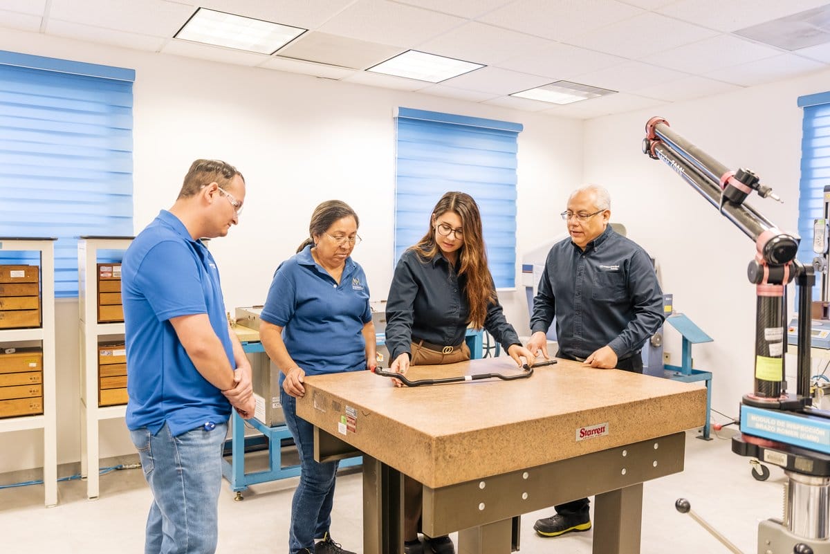 Engineers inspecting an automotive part at a Tetakawi Manufacturing Campus in Mexico | Tetakawi