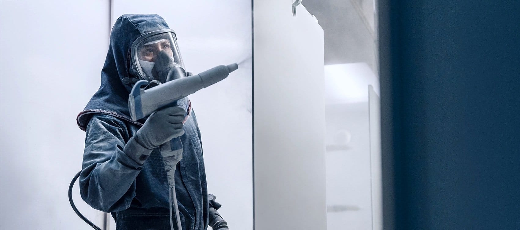 Tetakawi manufacturing worker in protective gear operating a paint spray booth, part of a stable workforce in Mexico | Tetakawi