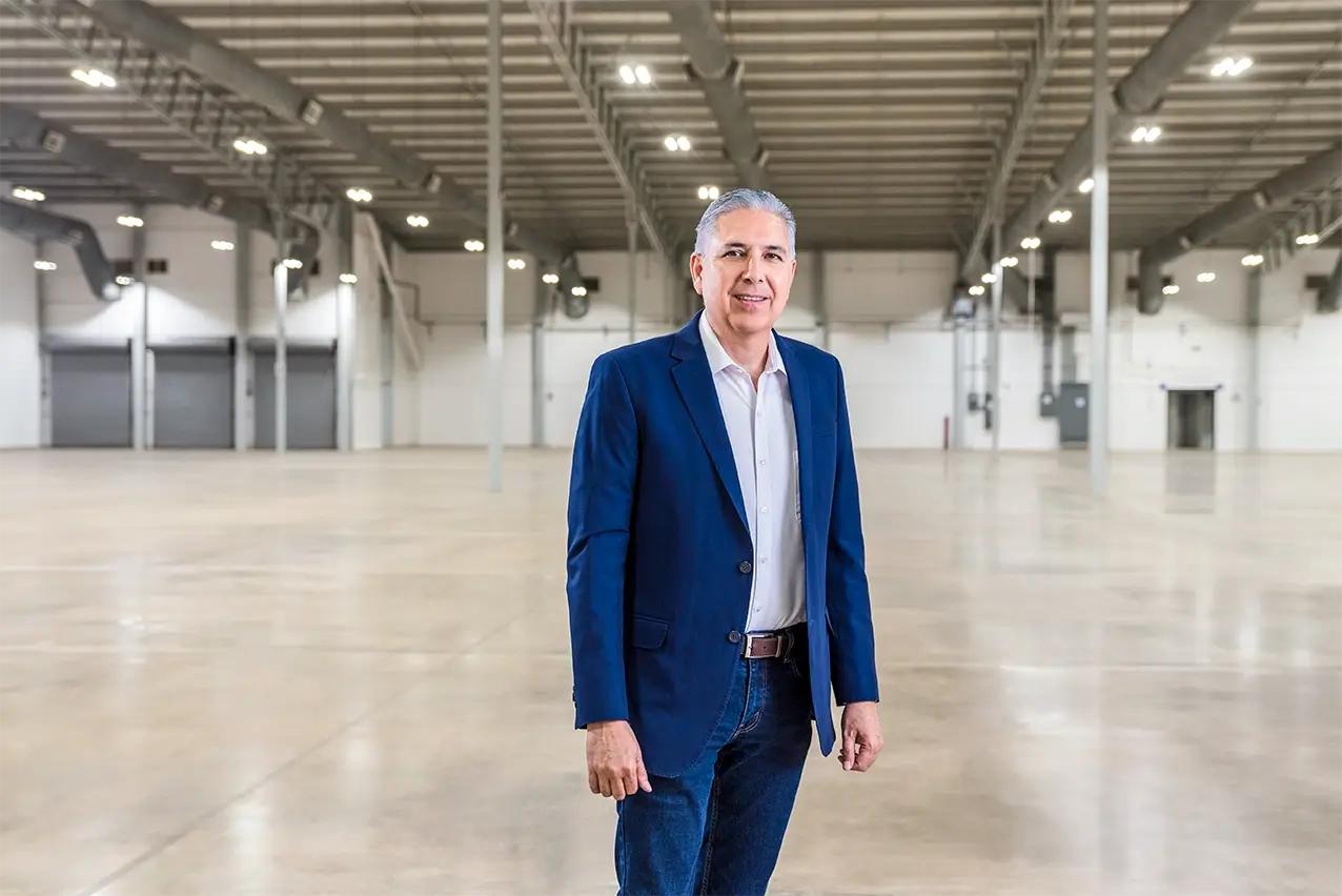 Man in a blue blazer standing inside an empty, newly built industrial building ready for manufacturing in Mexico | Tetakawi