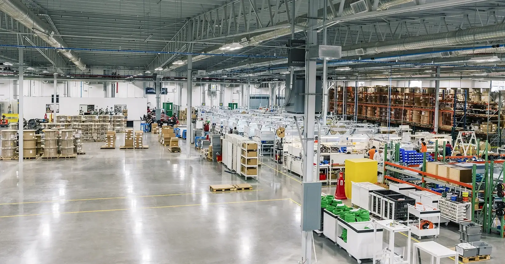 Wide view of a manufacturing floor with cable spools, assembly workstations and parts racks in Mexico | Tetakawi