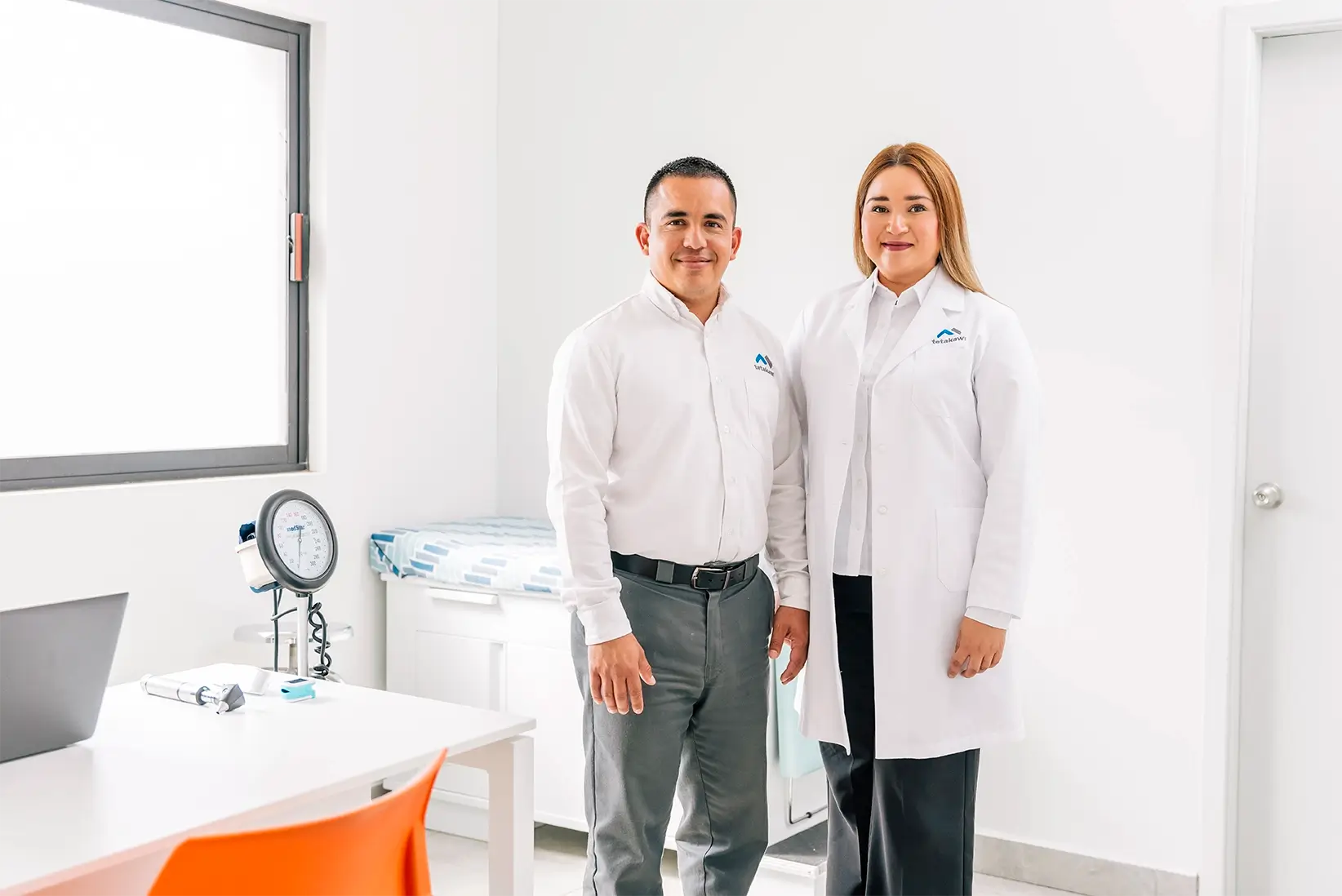 Tetakawi team members, one in a white lab coat, in a medical exam room on a Manufacturing Campus in Mexico | Tetakawi