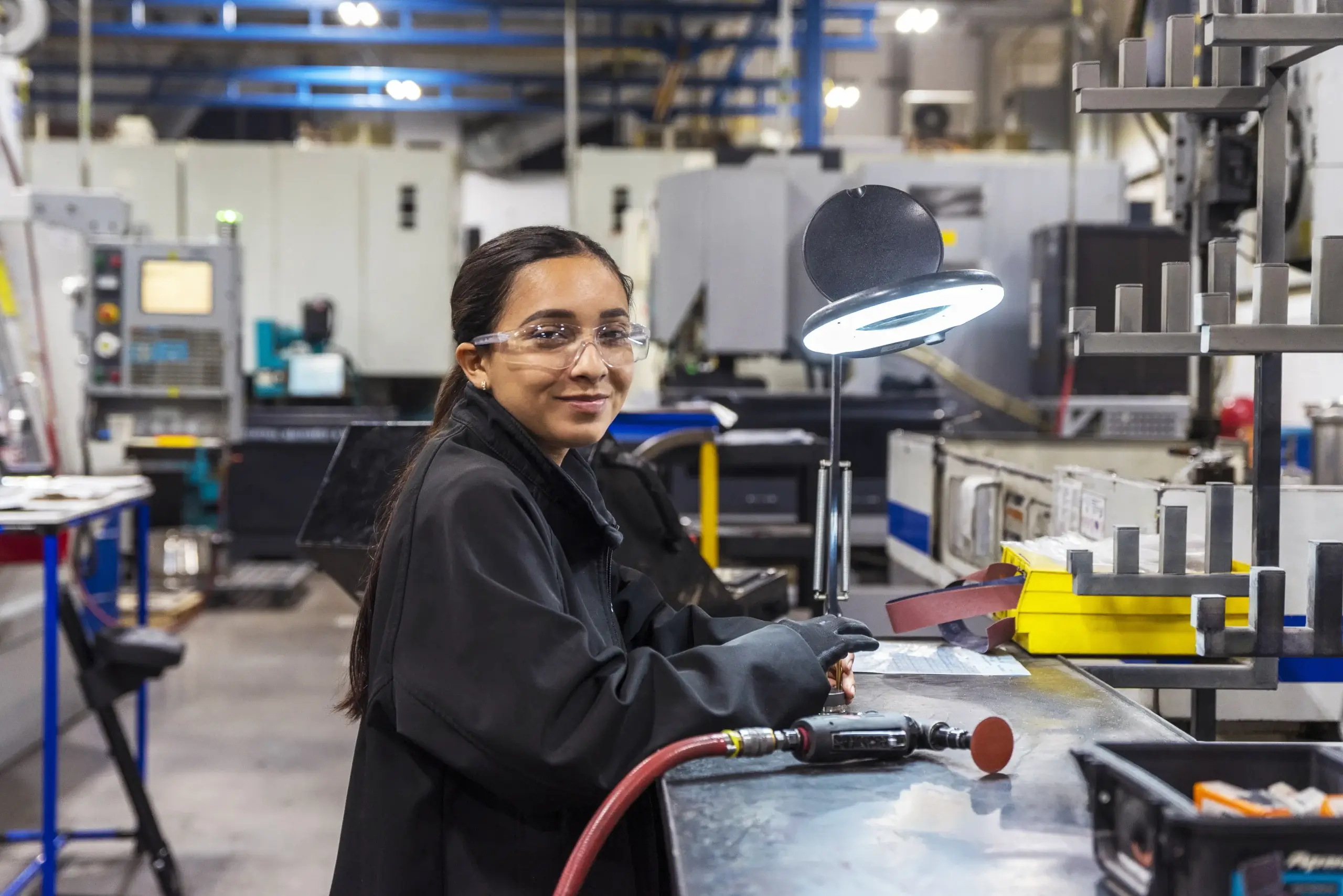 Technician in safety glasses at a workstation on a Manufacturing Campus production floor in Mexico | Tetakawi