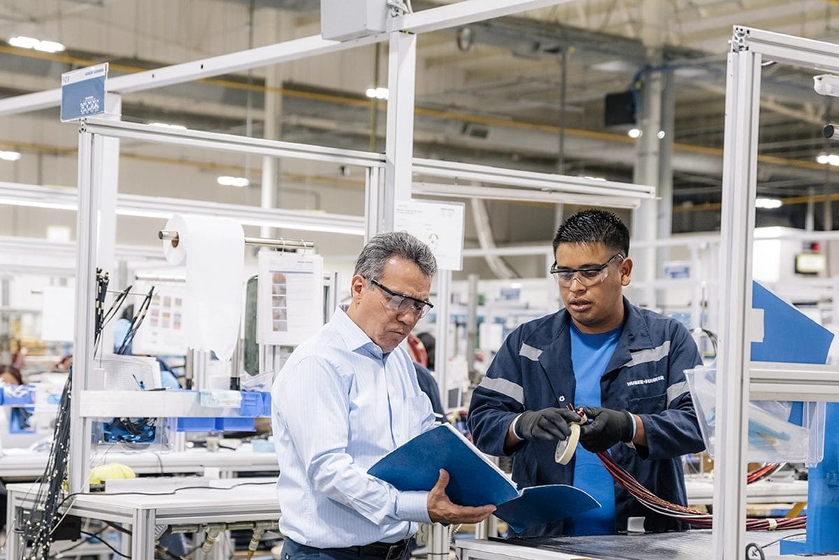HUBER+SUHNER team reviewing production documentation on the manufacturing floor at their Tetakawi campus in Mexico | Tetakawi