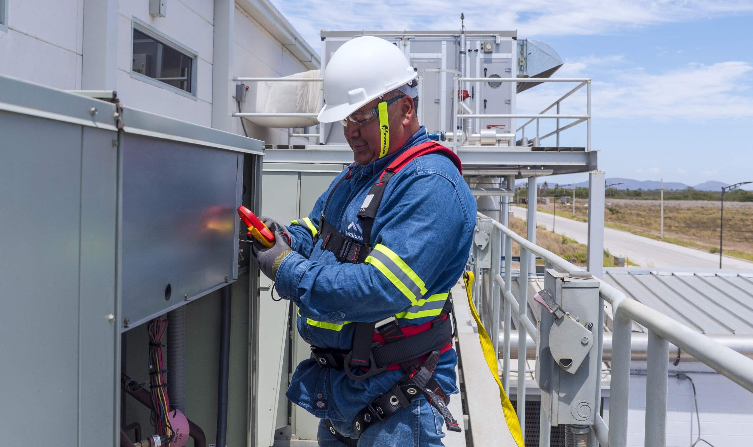 Facilities maintenance technician servicing rooftop HVAC equipment at a Tetakawi Campus in Mexico