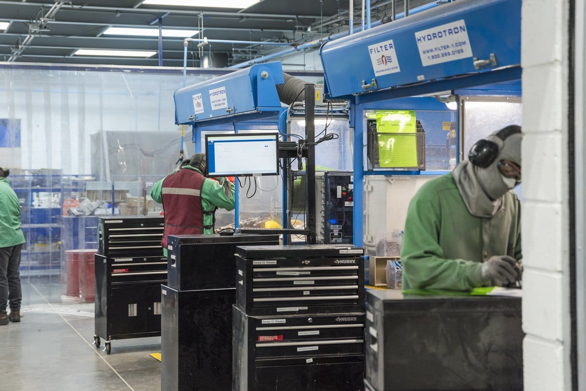 Tetakawi technicians in PPE work at finishing stations on a Manufacturing Campus production floor in Mexico | Tetakawi