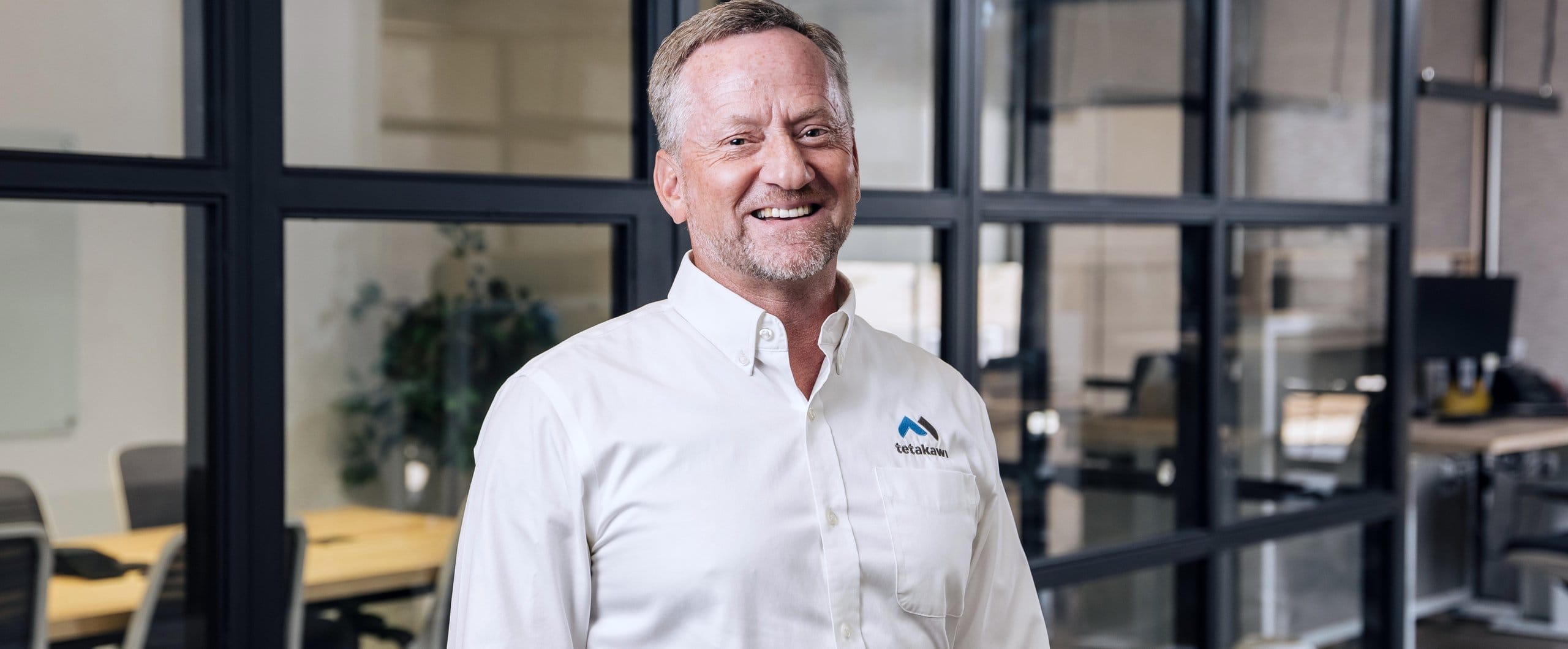 Tetakawi senior team leader smiling in a modern office, ready to support manufacturing plants in Mexico | Tetakawi