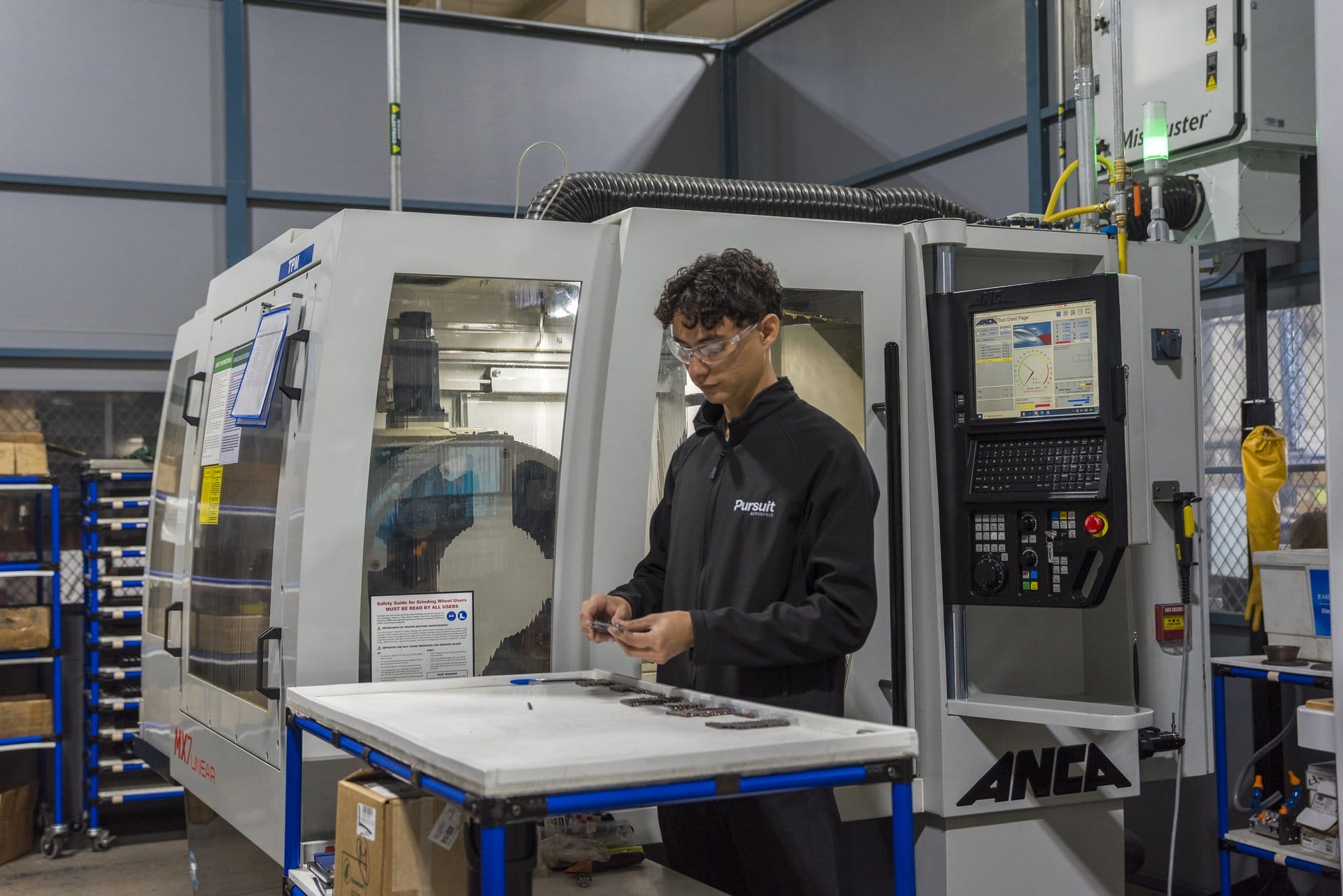 Pursuit Aerospace machinist inspecting precision engine components at a CNC grinding machine on Tetakawi's Roca Fuerte Campus in Guaymas, Mexico | Tetakawi